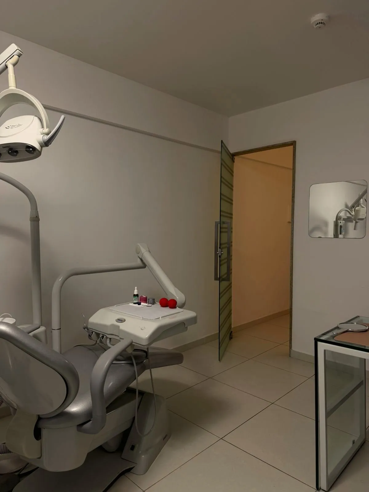 Sala de atendimento com cadeira odontológica, refletor e armário de instrumentos